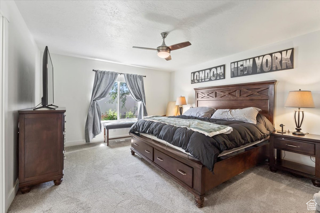 Bedroom featuring light colored carpet, a ceiling fan, baseboards, and a textured ceiling