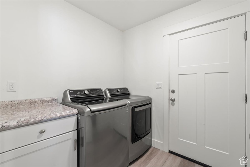 Laundry area with separate washer and dryer and light wood-style flooring