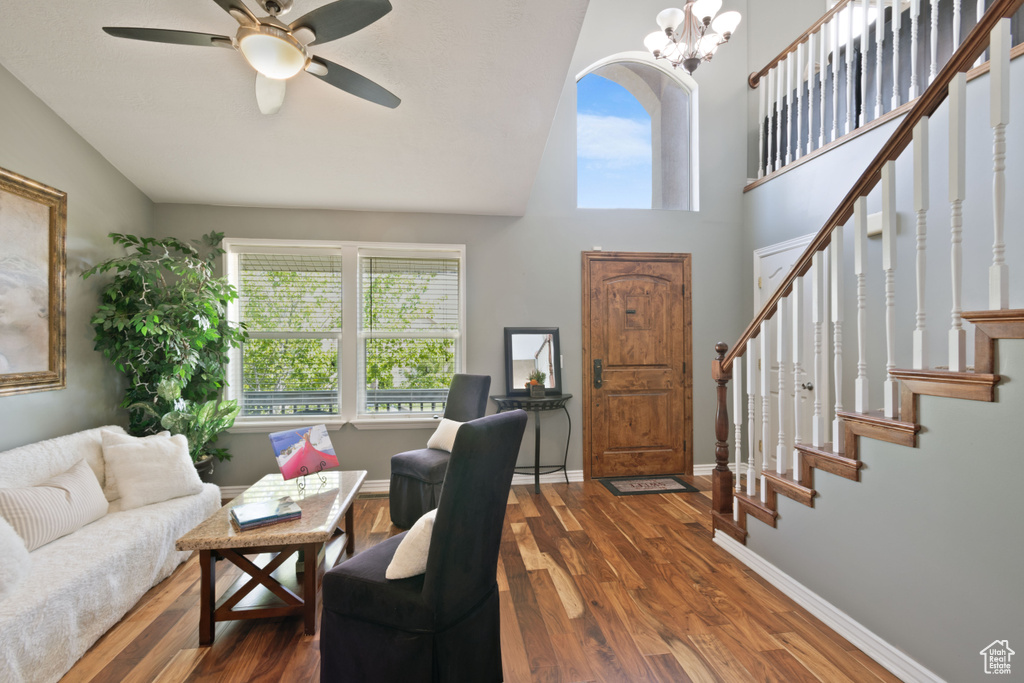 Living area featuring wood finished floors, a ceiling fan, stairs, high vaulted ceiling, and baseboards