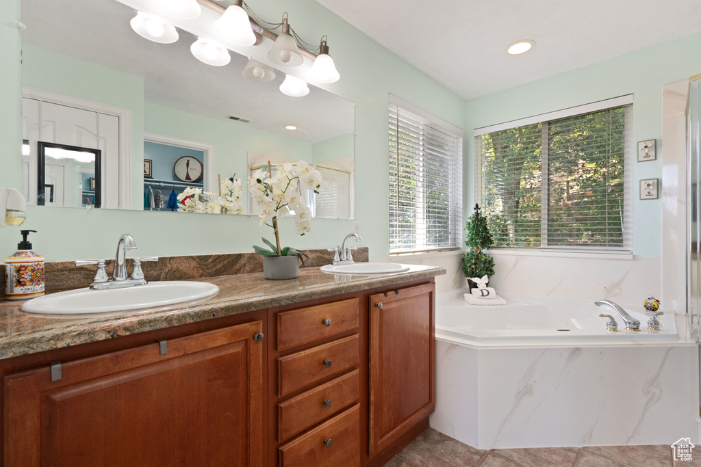 Bathroom featuring a garden tub, double vanity, and tile patterned floors