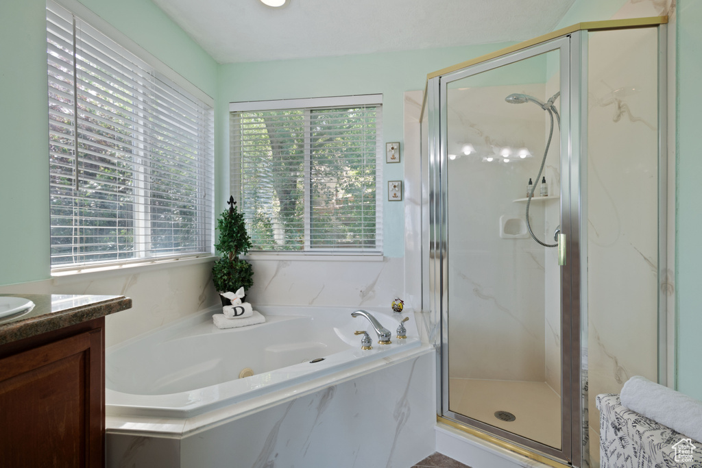 Bathroom featuring plenty of natural light, a stall shower, vanity, and a garden tub