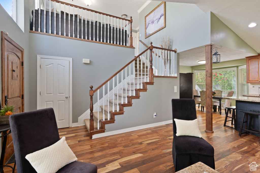 Living room with stairway, wood finished floors, a high ceiling, baseboards, and recessed lighting