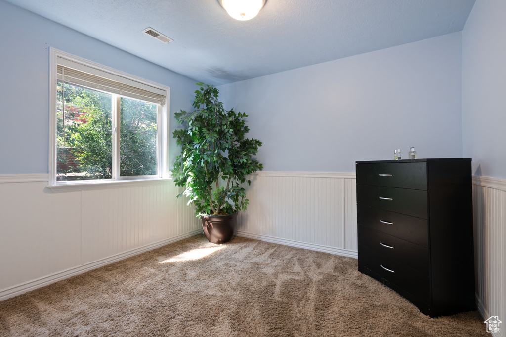 Carpeted empty room featuring wainscoting
