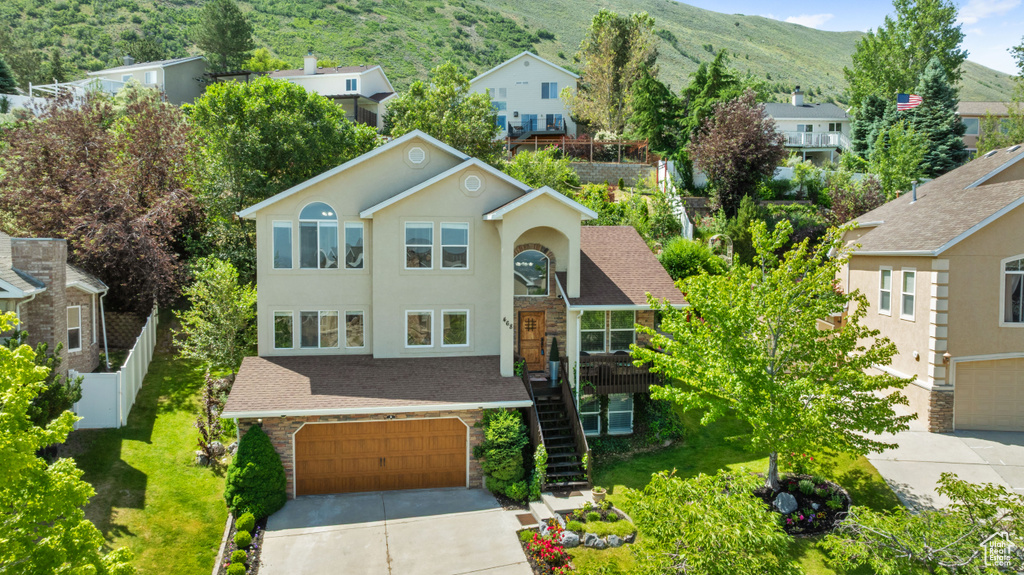 View of front facade with a garage, stairs, concrete driveway, a mountain view, and stone siding