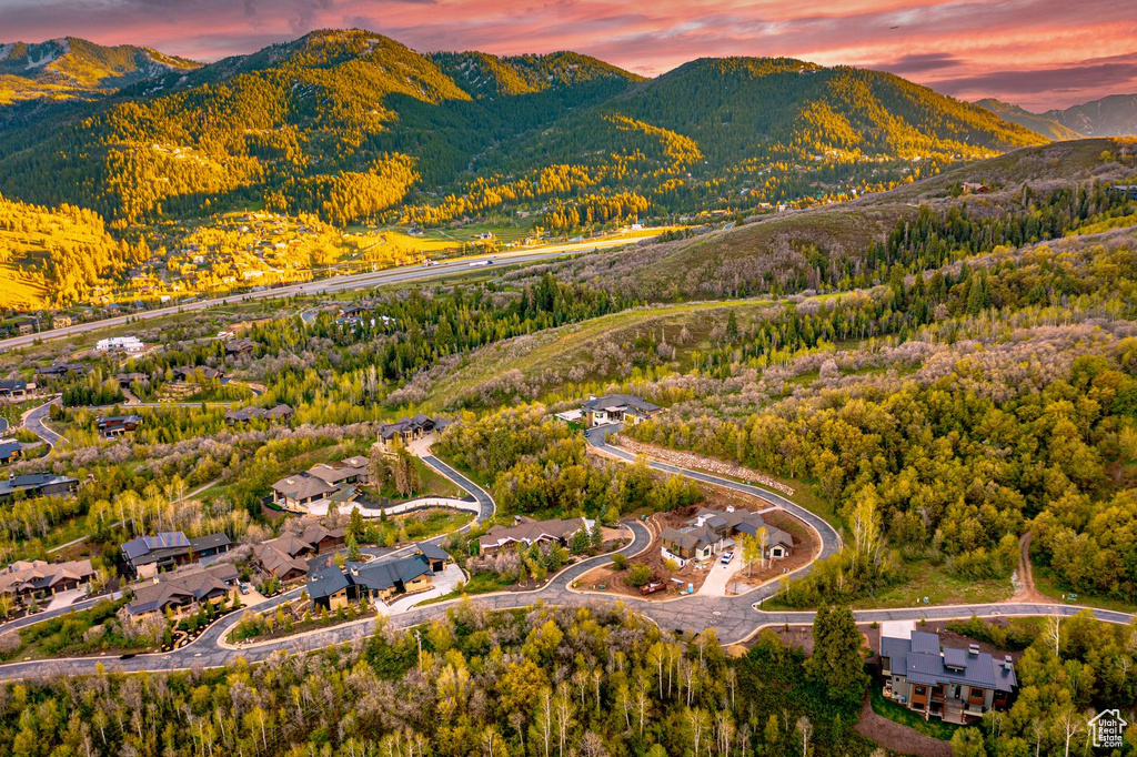 Aerial view of property and surrounding area featuring mountains and a heavily wooded area