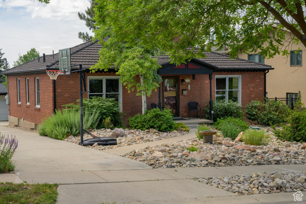 View of front facade featuring a tiled roof, brick siding, and concrete driveway