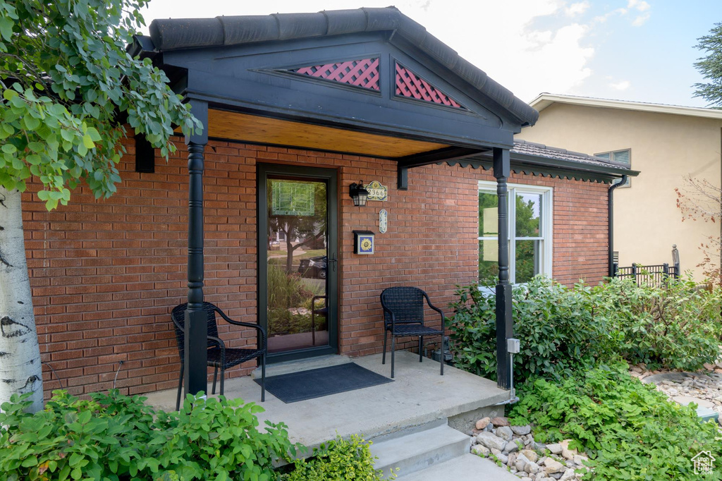 Doorway to property with covered porch and brick siding