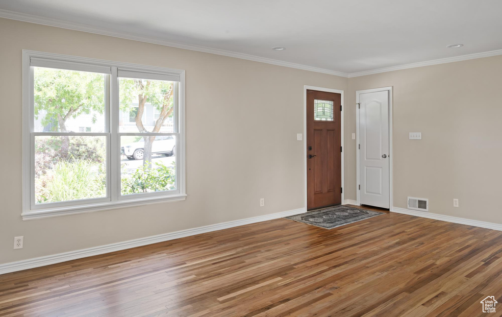 Foyer entrance featuring wood finished floors, baseboards, and ornamental molding