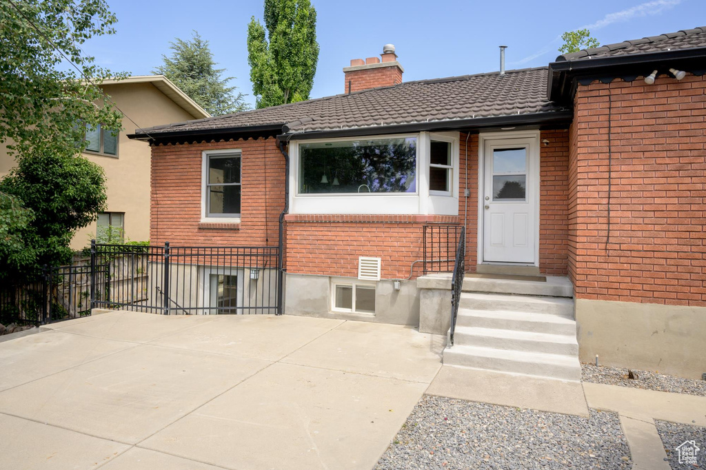 Back of property featuring a chimney and brick siding