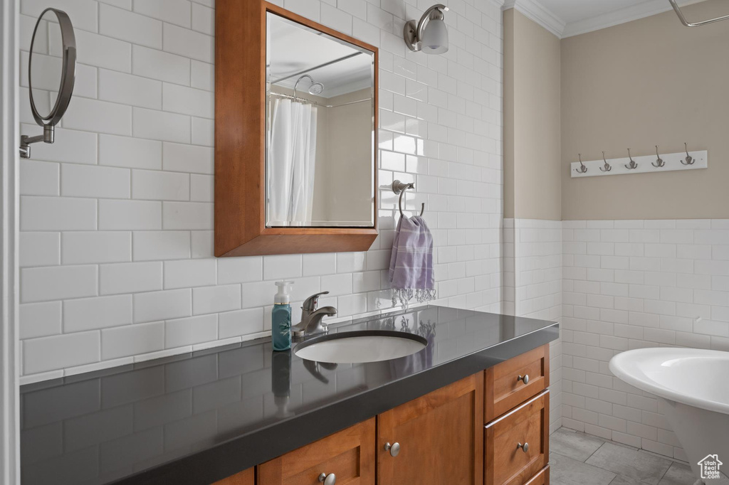 Bathroom with tile walls, a sink, crown molding, tile patterned flooring, and curtained shower
