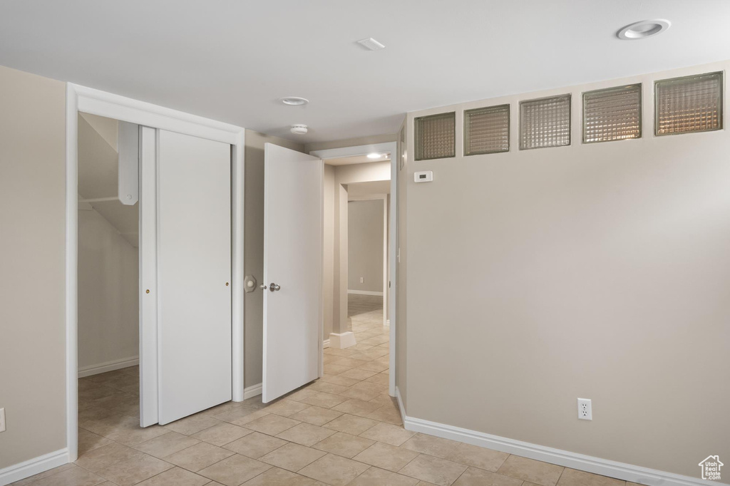 Empty room featuring baseboards, light tile patterned floors, and recessed lighting