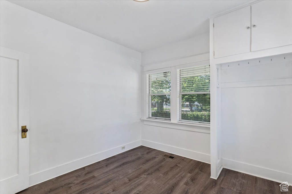 Empty room featuring dark wood-style flooring and baseboards