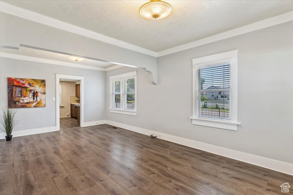 Spare room featuring dark wood finished floors, baseboards, and ornamental molding