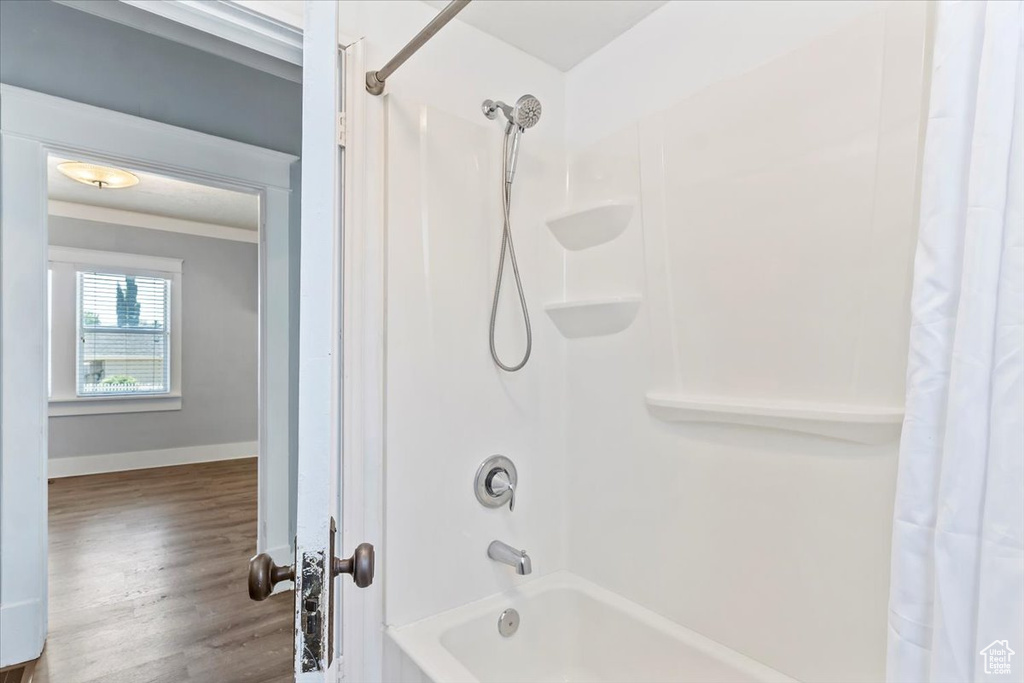 Bathroom with shower / tub combo, wood finished floors, baseboards, and crown molding