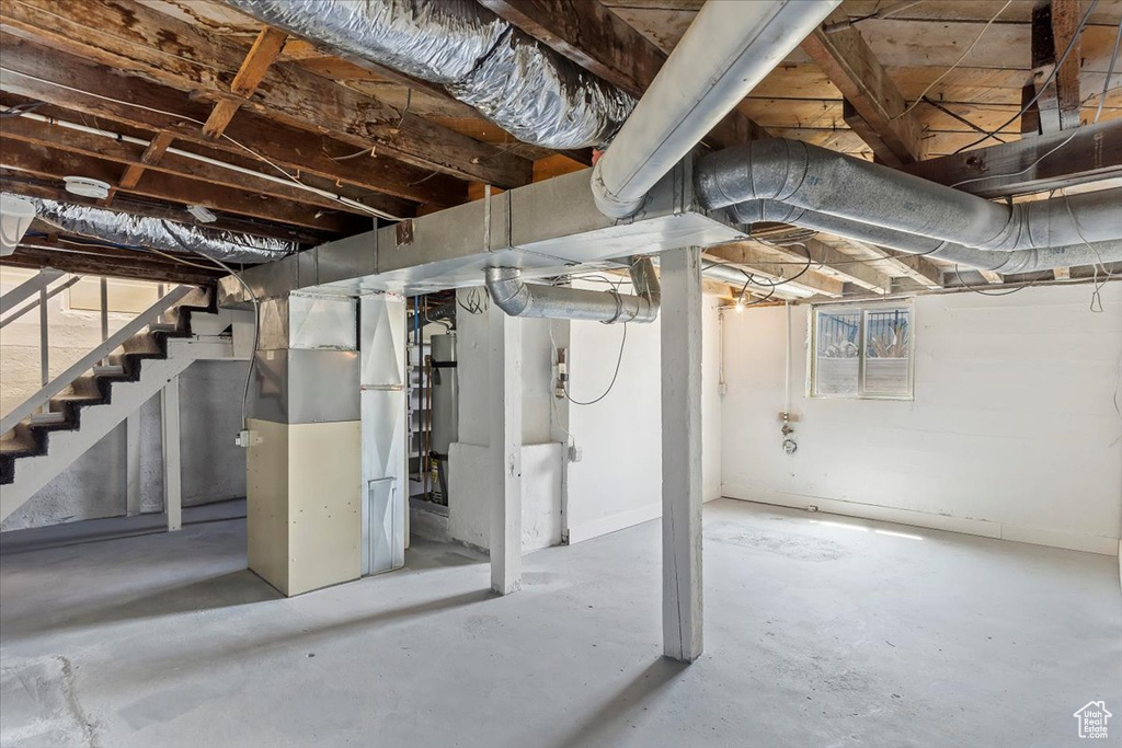 Basement featuring heating unit and stairs