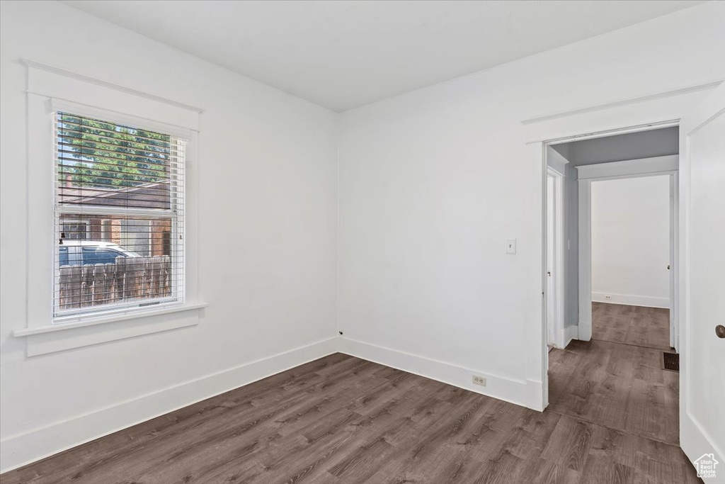 Empty room with dark wood-type flooring and baseboards