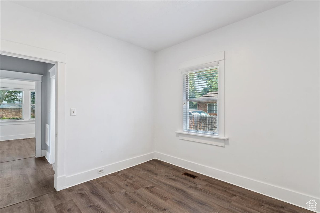 Unfurnished room with healthy amount of natural light, dark wood-style flooring, and baseboards
