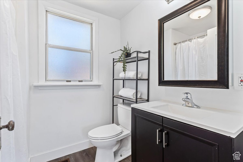 Bathroom with vanity, wood finished floors, toilet, and baseboards