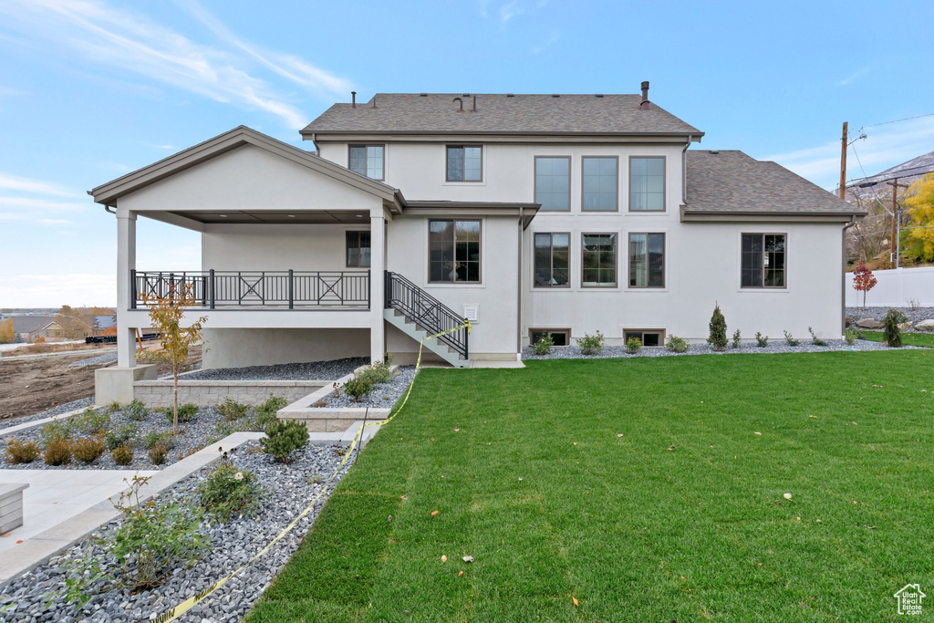 Rear view of property featuring stucco siding, stairway, and roof with shingles