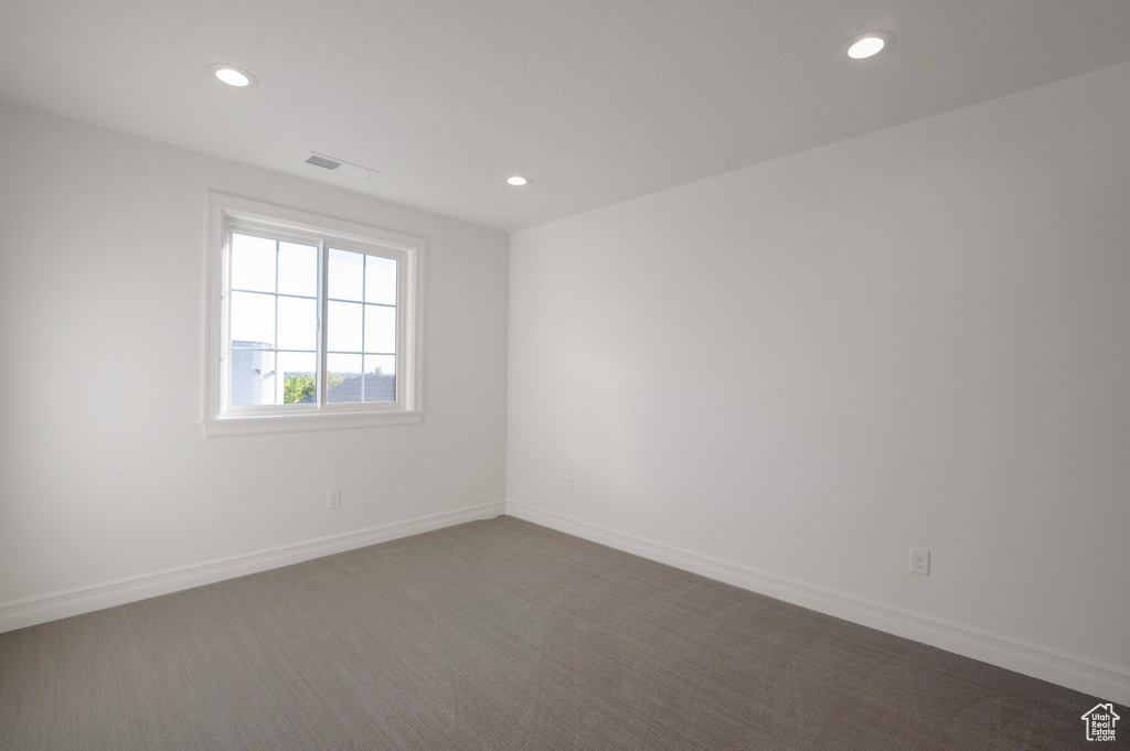 Empty room with recessed lighting, dark colored carpet, and baseboards