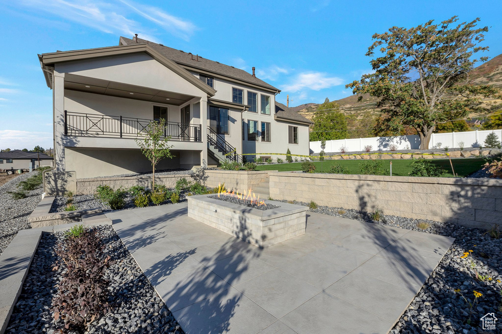 Back of property with stucco siding, an outdoor fire pit, a patio, and stairway