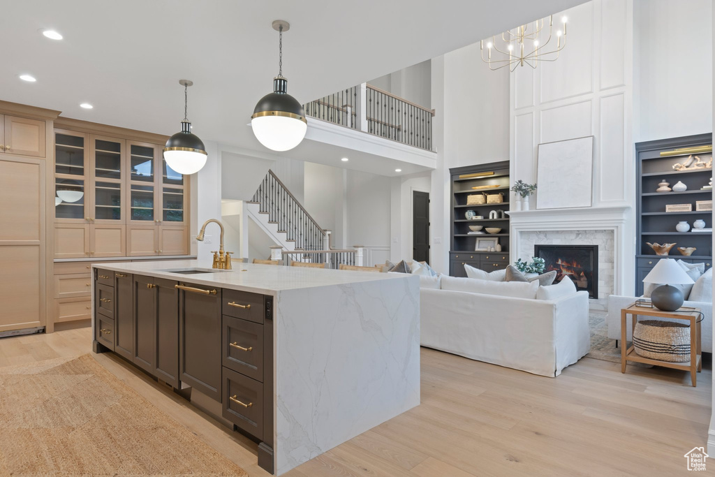 Kitchen featuring a sink, light wood finished floors, recessed lighting, a chandelier, and a center island with sink