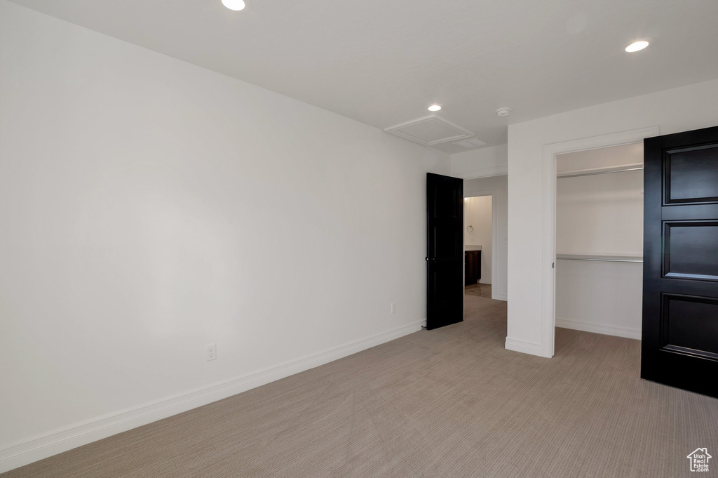 Unfurnished bedroom with attic access, light carpet, recessed lighting, baseboards, and a closet