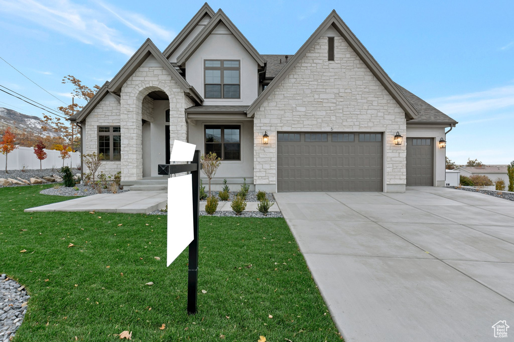 French provincial home with stone siding, an attached garage, stucco siding, concrete driveway, and a shingled roof