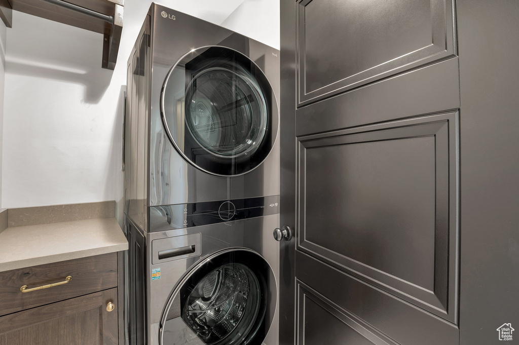 Laundry room featuring stacked washer / drying machine and cabinet space