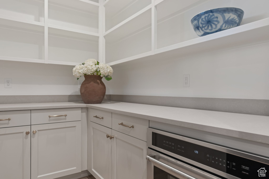 Kitchen with stainless steel oven, white cabinets, and light countertops