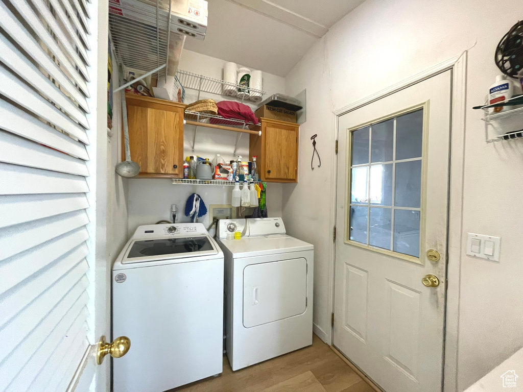 Laundry area featuring cabinet space, washing machine and clothes dryer, and light wood-style flooring