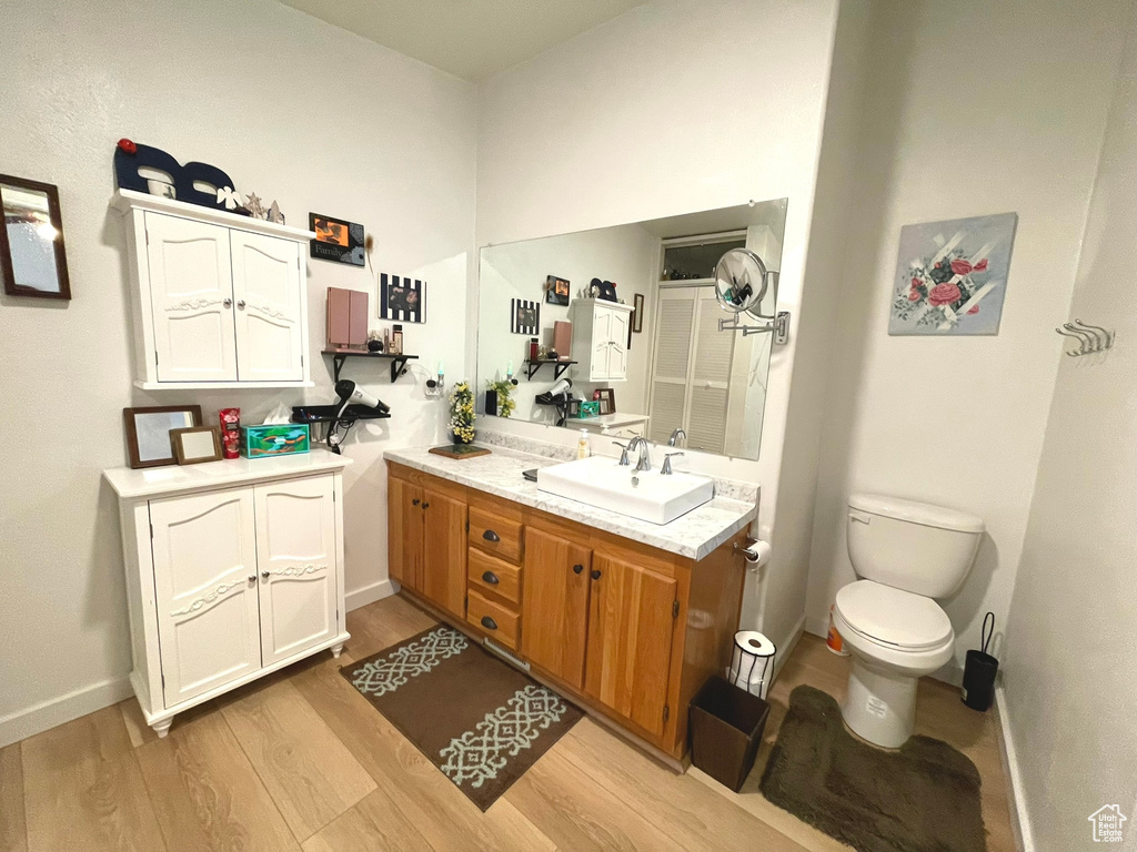 Bathroom featuring vanity, wood finished floors, toilet, and baseboards
