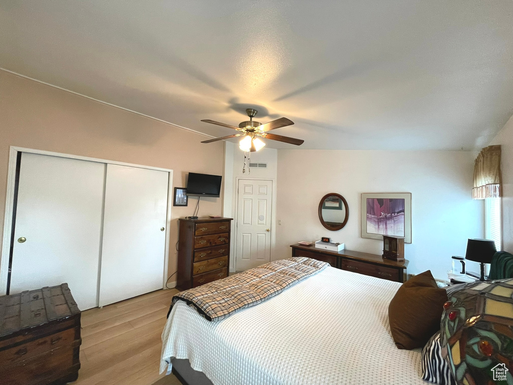 Bedroom featuring light wood-style floors, a closet, and ceiling fan