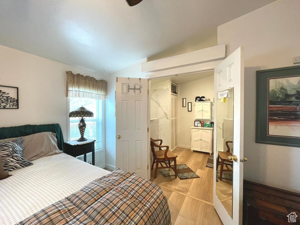 Bedroom with light wood-type flooring and vaulted ceiling