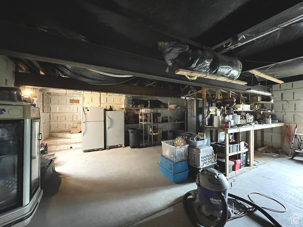 Unfinished basement with freestanding refrigerator