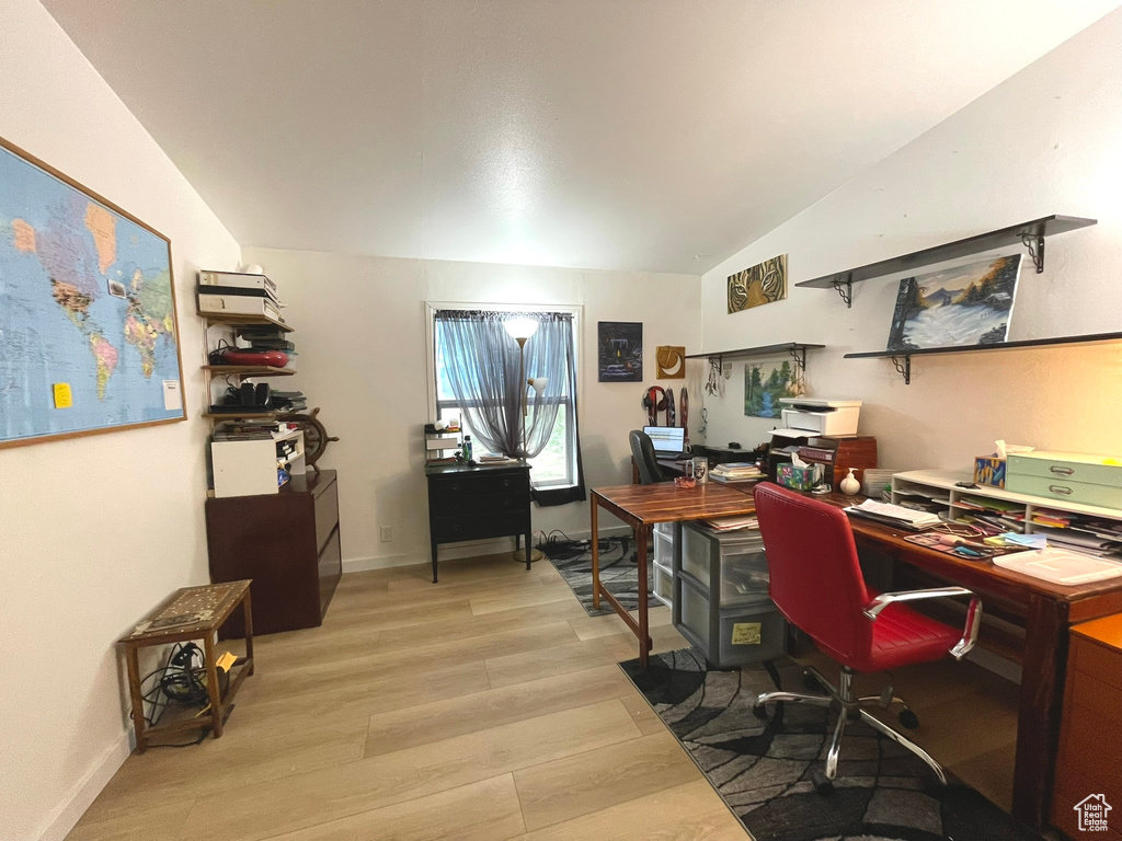 Office area featuring light wood-style floors and vaulted ceiling
