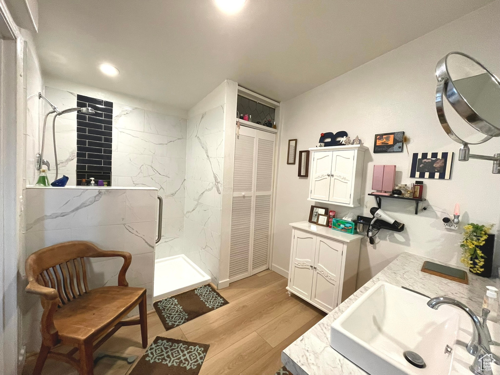 Bathroom featuring double vanity, a marble finish shower, wood finished floors, recessed lighting, and a closet