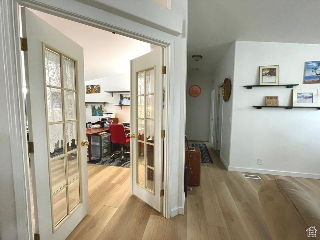 Corridor with an office area, light wood-style flooring, and baseboards