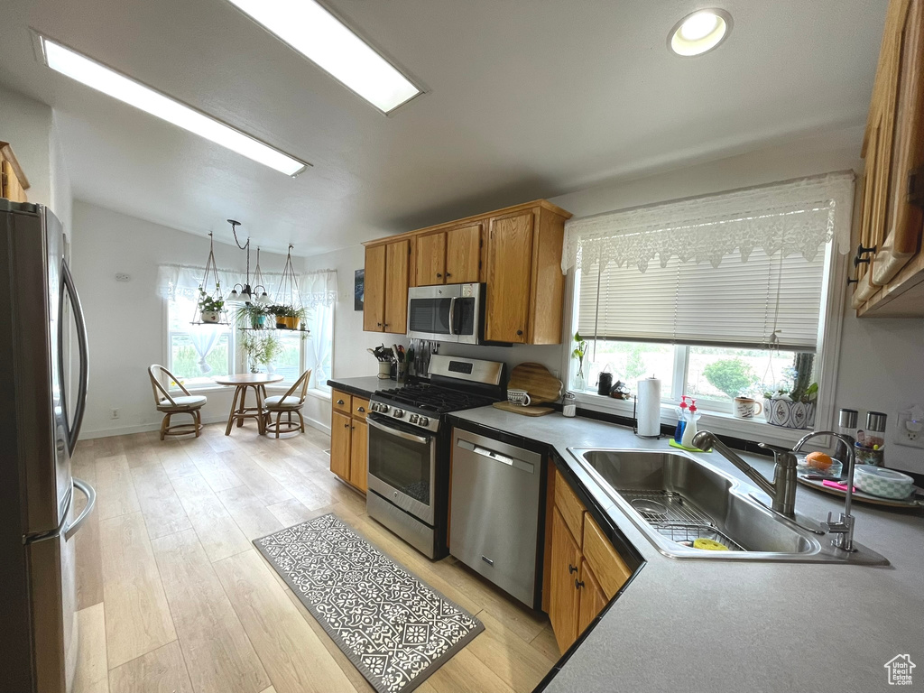 Kitchen featuring appliances with stainless steel finishes, a sink, brown cabinetry, decorative light fixtures, and recessed lighting
