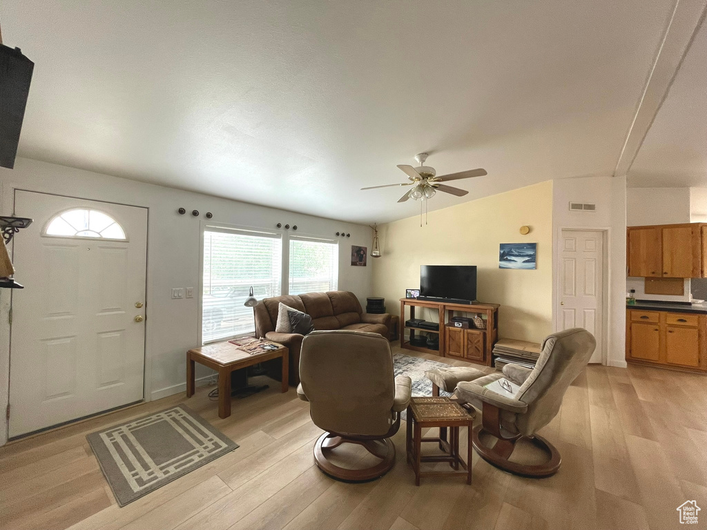 Living area featuring light wood-style floors, lofted ceiling, and ceiling fan