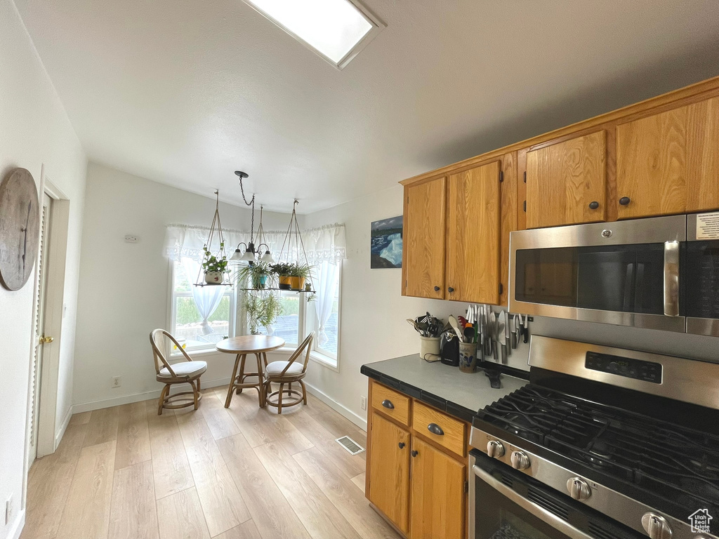 Kitchen featuring stainless steel appliances, light wood-style floors, baseboards, and brown cabinets