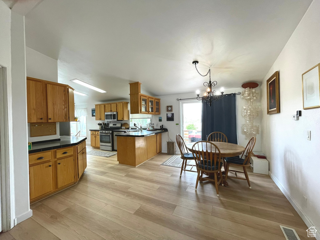 Dining space with a chandelier, light wood-style flooring, and baseboards