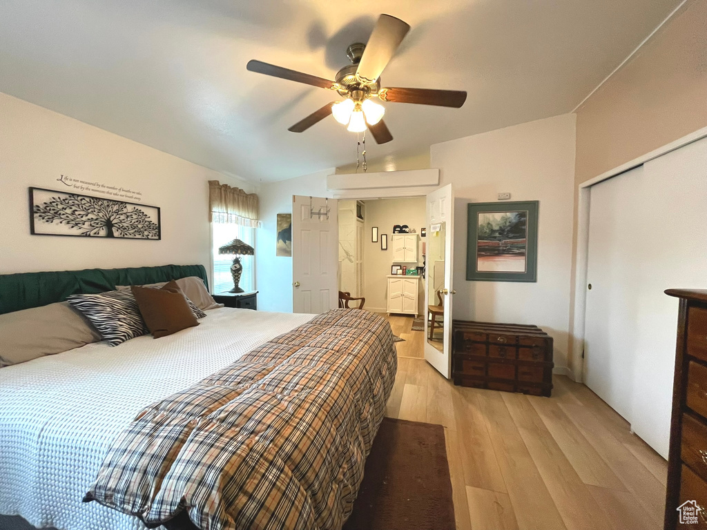 Bedroom featuring light wood-type flooring, a closet, lofted ceiling, and a ceiling fan