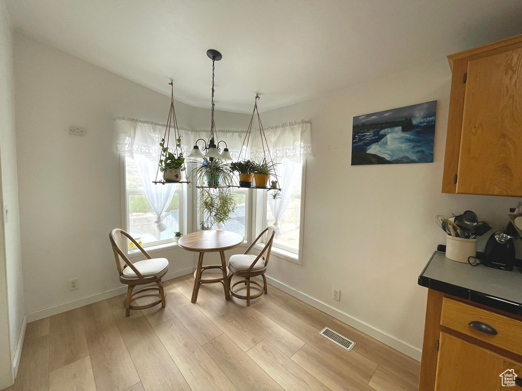 Dining space with light wood finished floors, healthy amount of natural light, baseboards, and vaulted ceiling