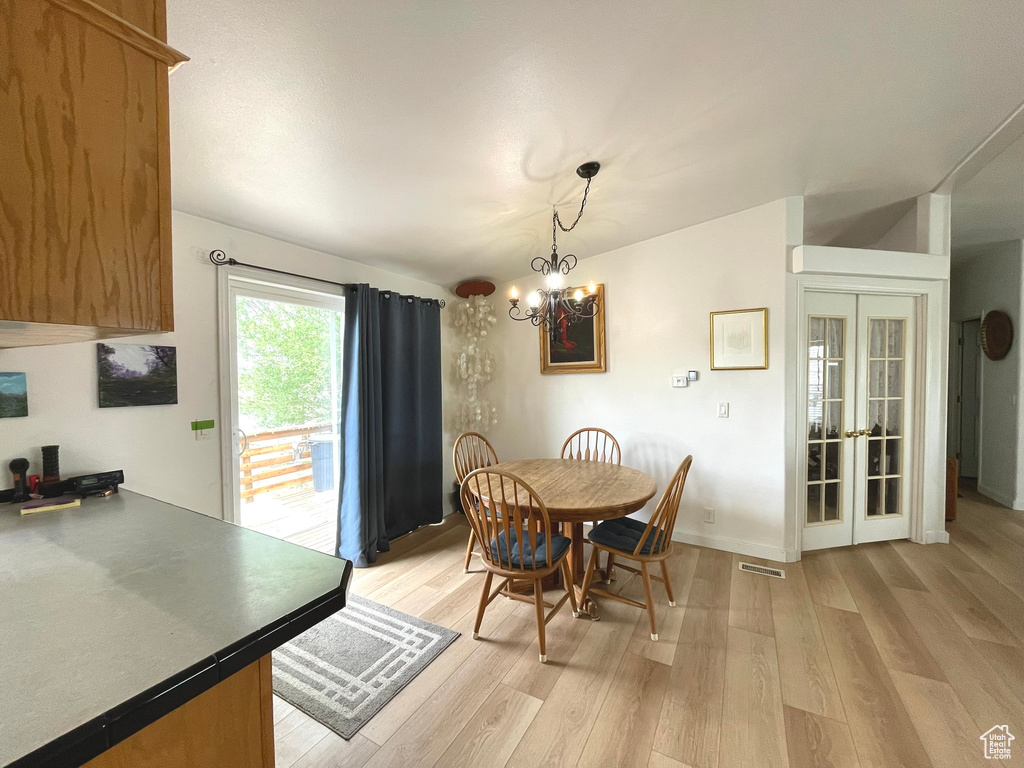 Dining area with light wood-type flooring, a chandelier, french doors, and baseboards