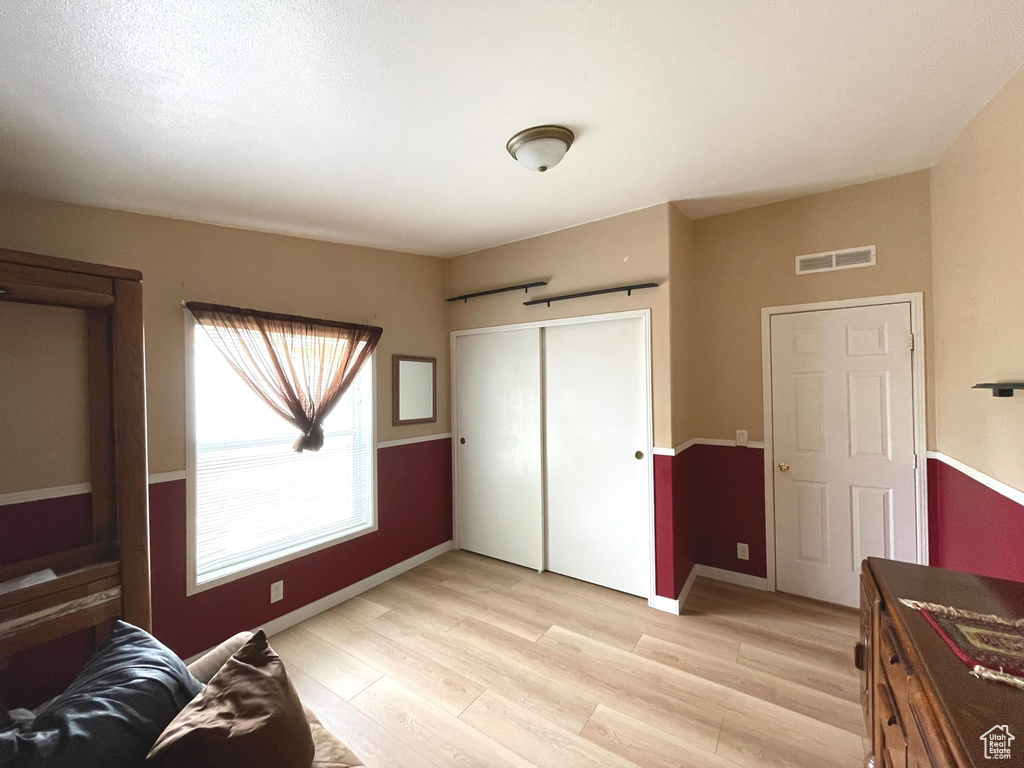 Bedroom with light wood finished floors, baseboards, and a closet