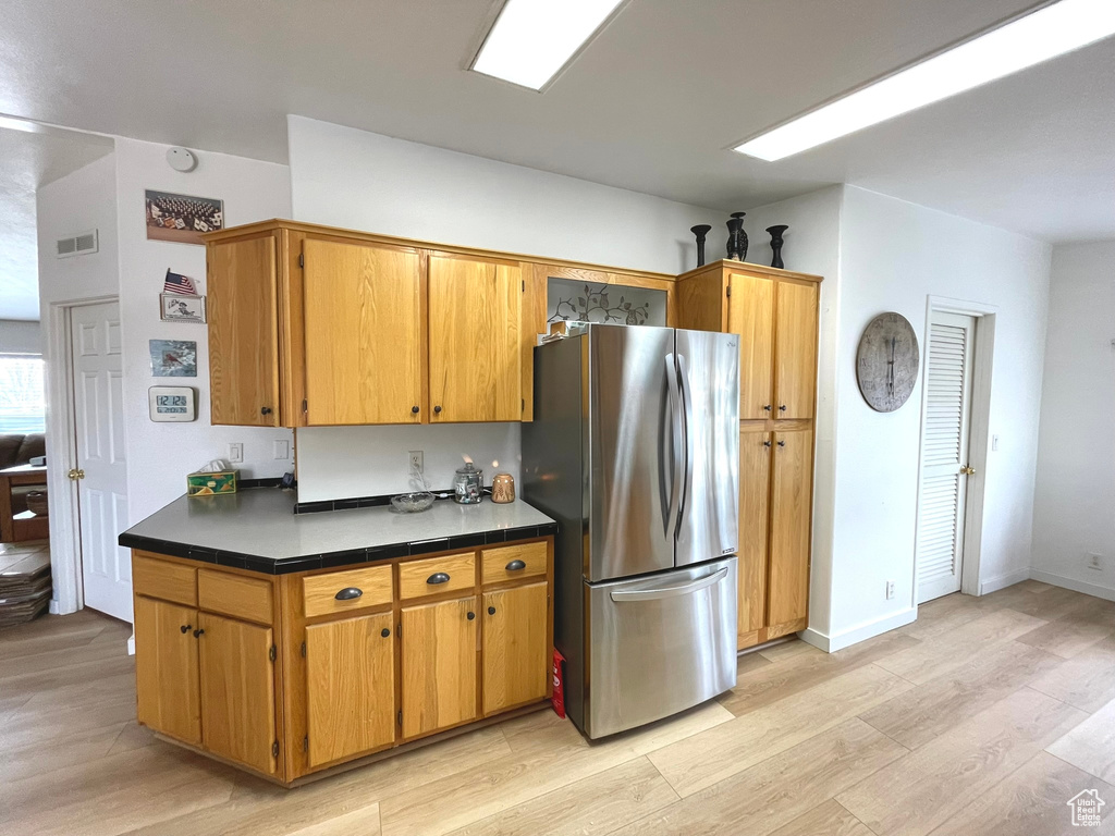 Kitchen with freestanding refrigerator and light wood-style floors