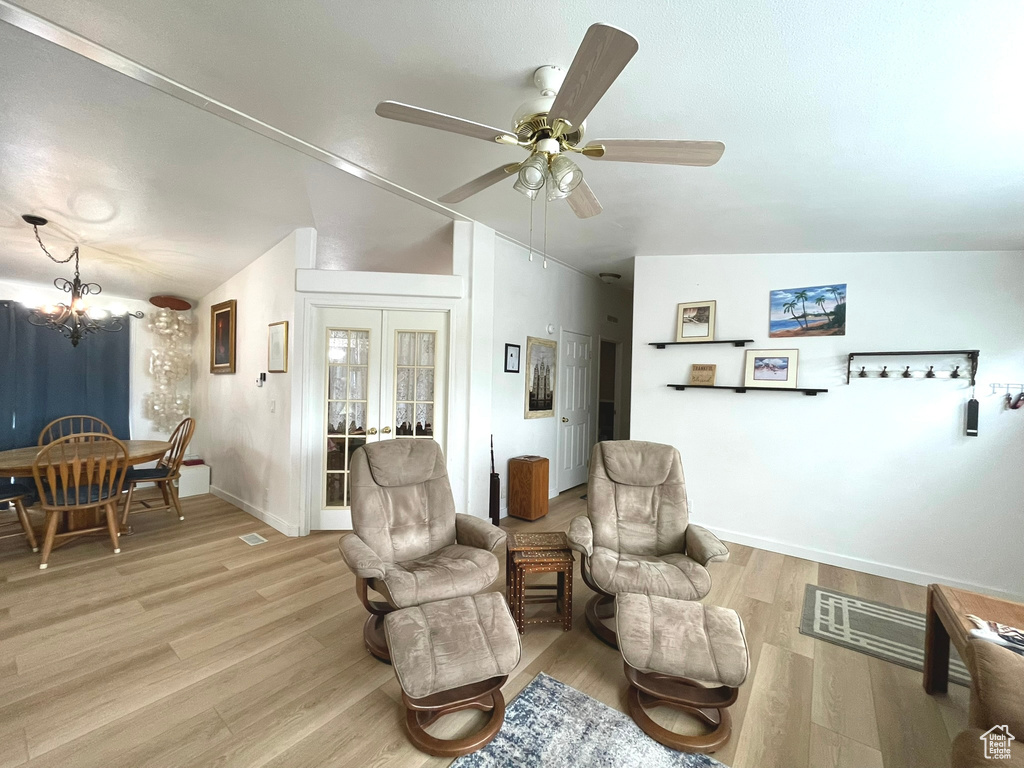 Living area with a ceiling fan, light wood-type flooring, a chandelier, and baseboards