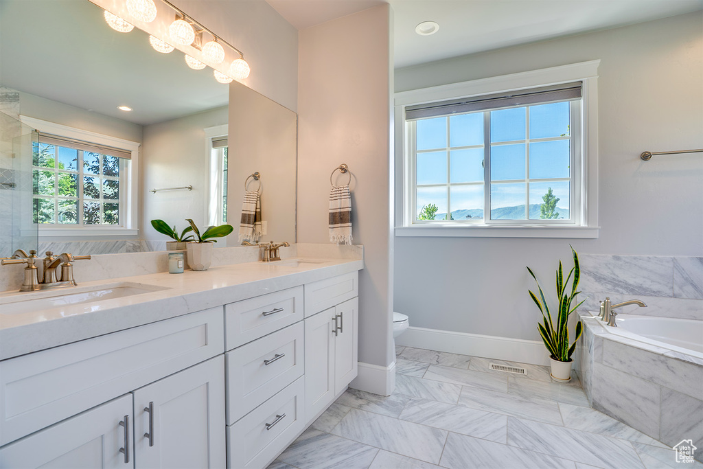 Full bath featuring double vanity, a bath, toilet, marble look tile flooring, and a shower