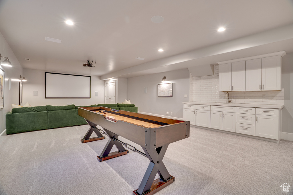 Recreation room with light colored carpet, recessed lighting, a sink, and baseboards